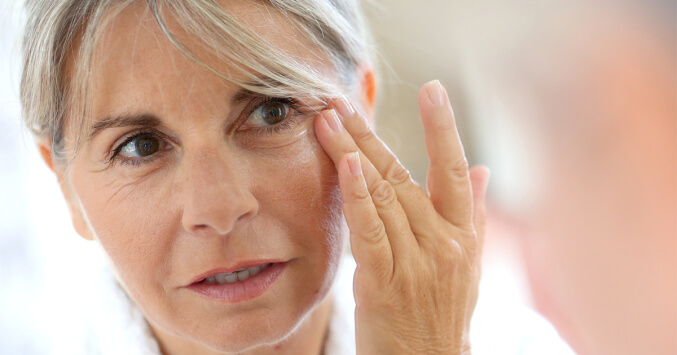 Woman examining her eyes Eyelid Surgery